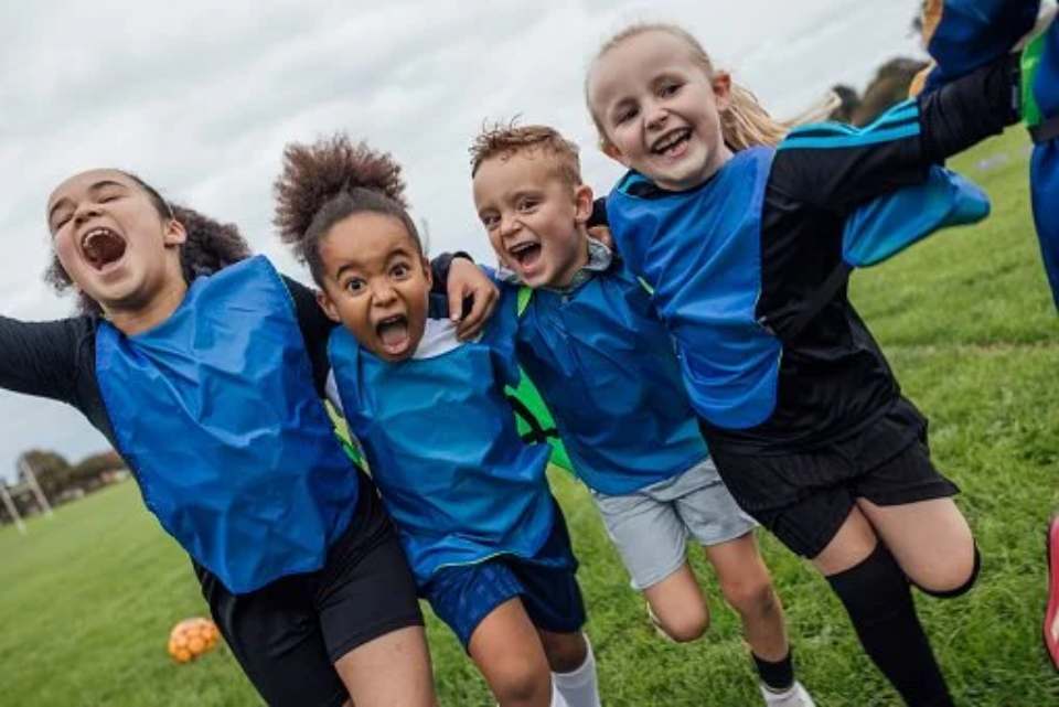 Kids in team jerseys cheering together on a soccer field